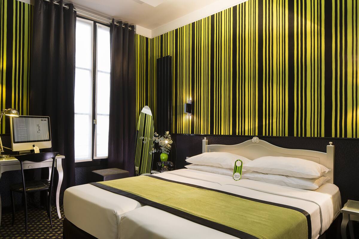 A hotel room with a large bed, a desk with a computer, and a chair.