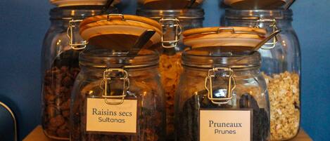 Glass jars with metal lids and labels on a wooden shelf against a blue wall.