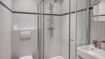 A bathroom with a glass-enclosed shower, a white toilet, and a sink with a mirror.