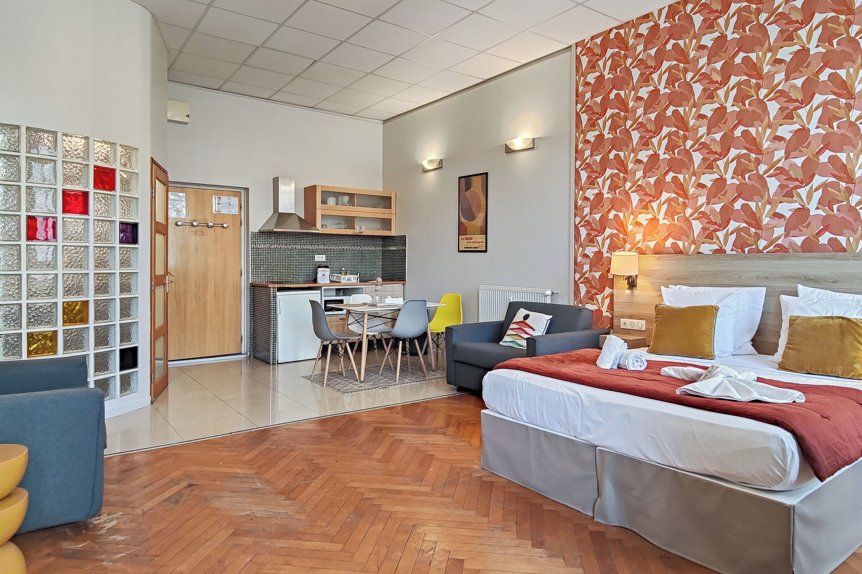 Una habitación de hotel con cama, sofá, zona de comedor y cocina al fondo.