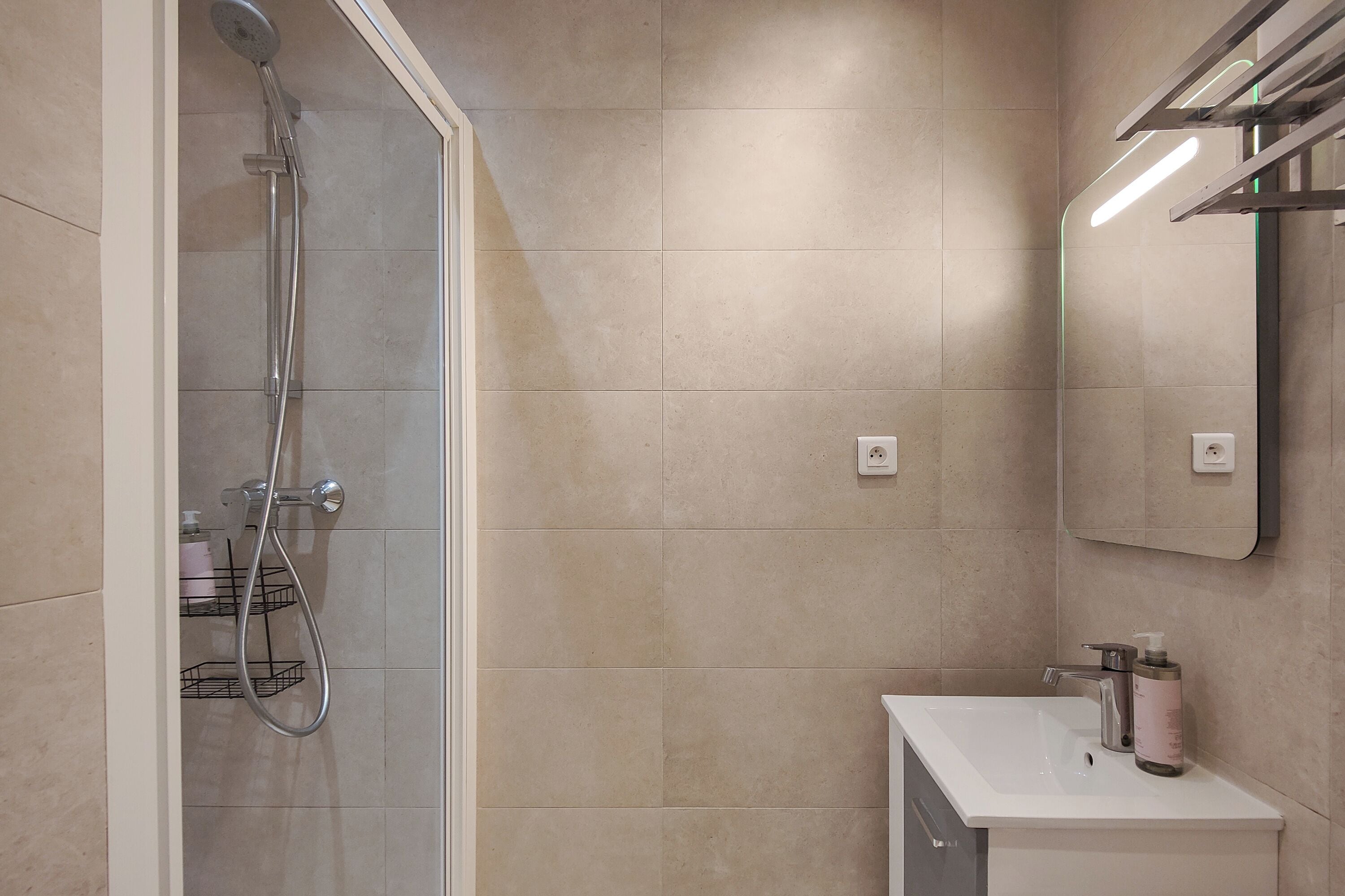 A bathroom with a shower, sink, and mirror.