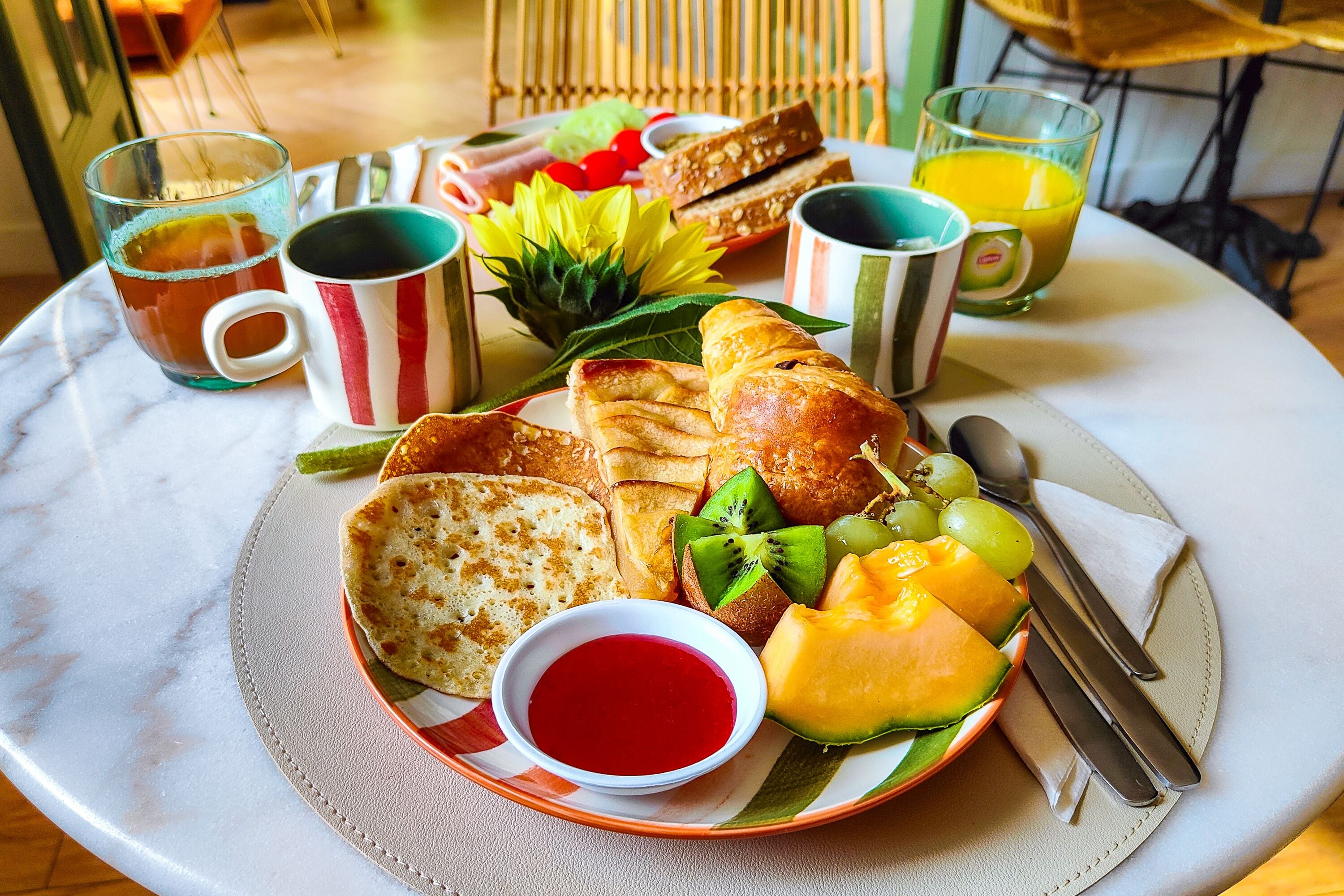 A breakfast setting with toast, fruit, and beverages on a table.