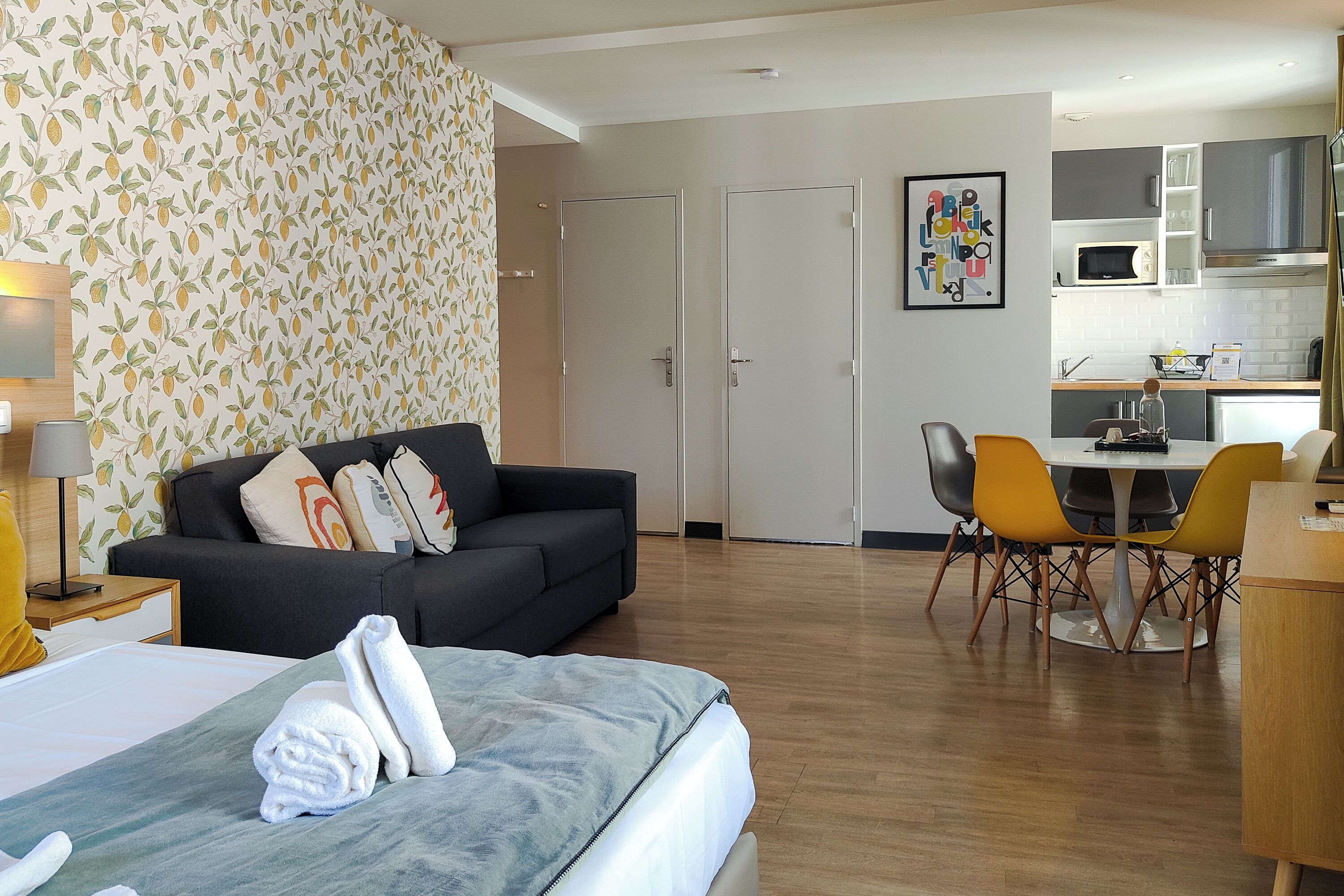 Een hotelkamer met een bed, een bank, een eettafel met stoelen, een keuken en een badkamer.