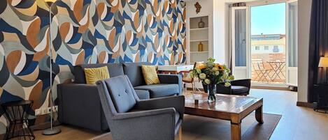 A modern living room with a grey sofa, a coffee table, and a patterned wall.