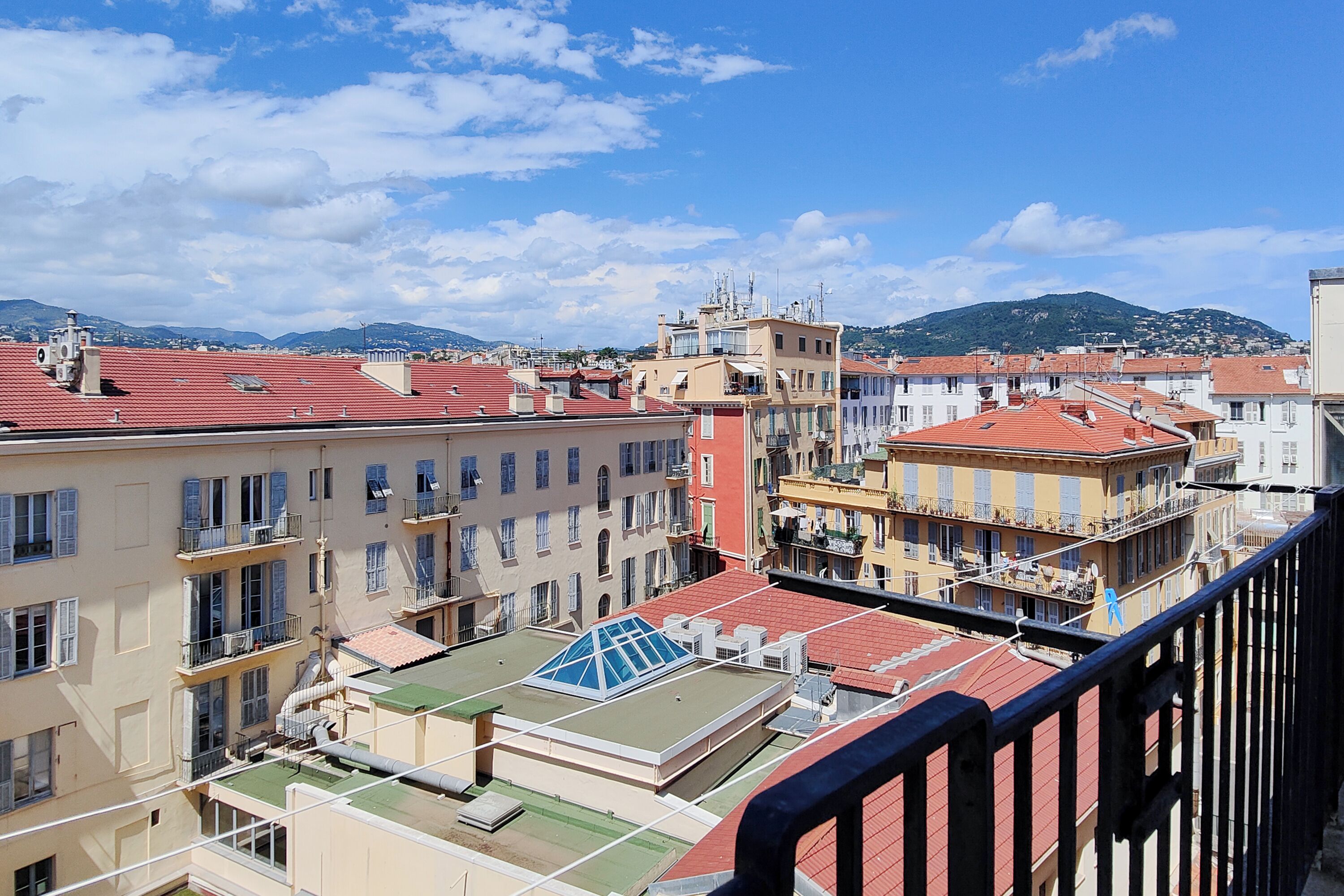 A cityscape with multi-story buildings, balconies, and a clear sky.