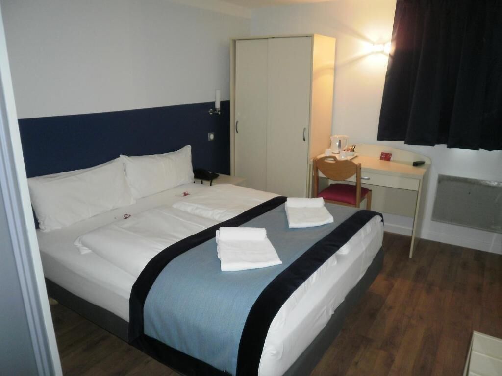 Una habitación de hotel con cama, escritorio, silla y armario.