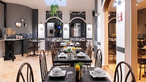 Un comedor con mesas dispuestas para cuatro, sillas, una zona de bar y vistas a la cocina.