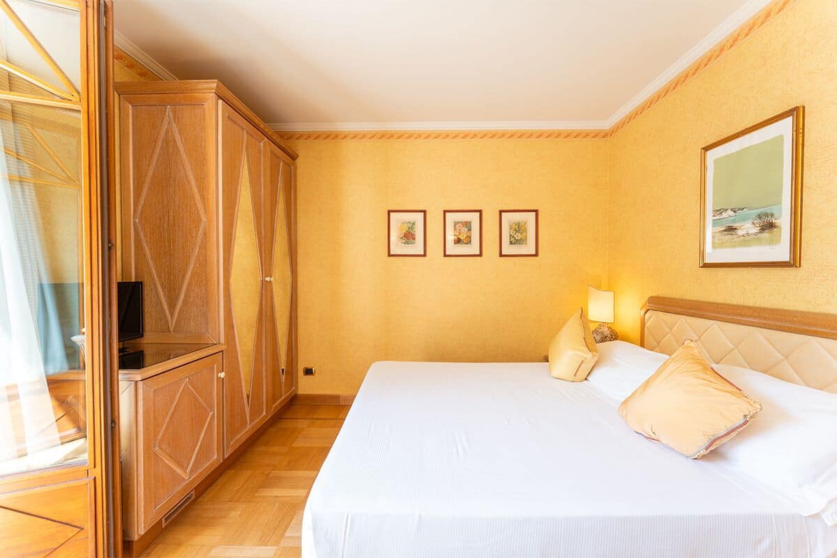 Ein Hotelzimmer mit einem großen Bett, einem Kleiderschrank und drei gerahmten Bildern an der Wand.