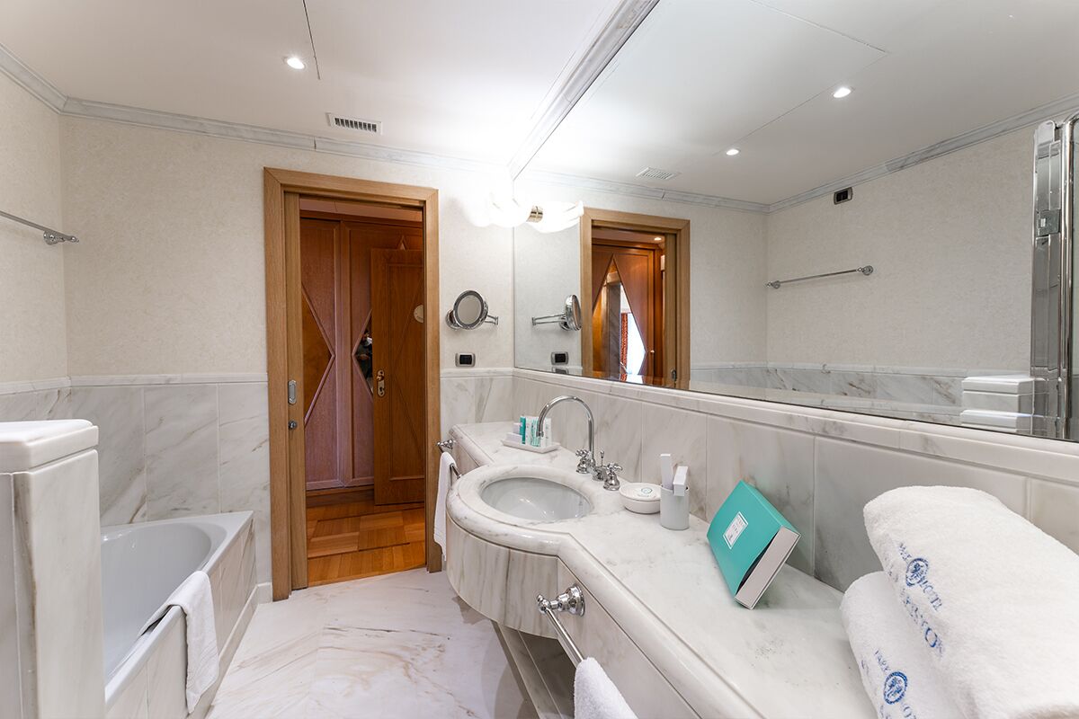 A modern bathroom with a bathtub, two sinks, a large mirror, and a shower area.