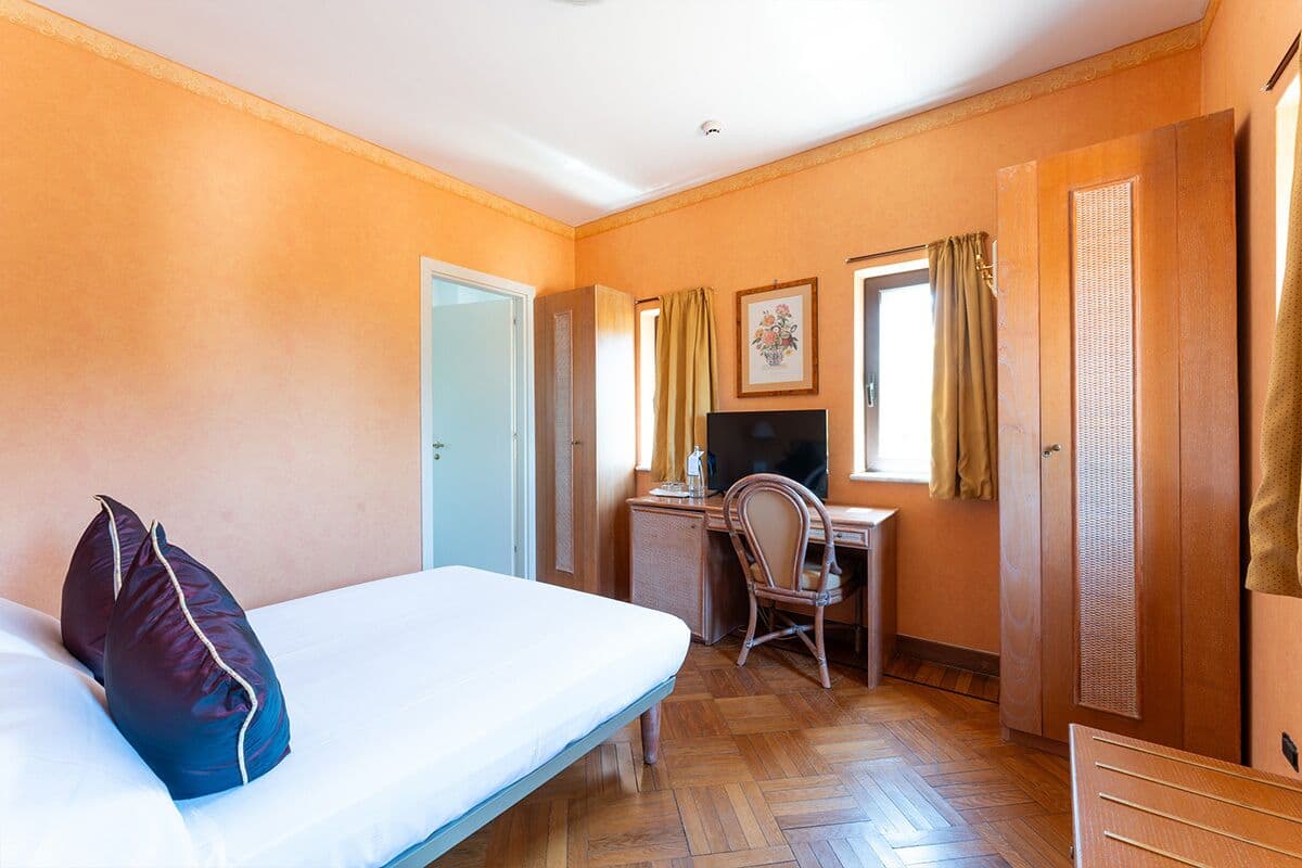 Ein Hotelzimmer mit Bett, Schreibtisch mit Computer, Stuhl und Kleiderschrank.