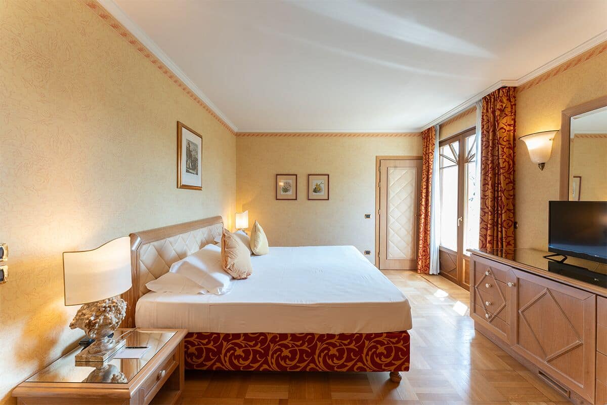 Ein Hotelzimmer mit einem großen Bett, einem Fernseher, einem Nachttisch und einer Kommode.