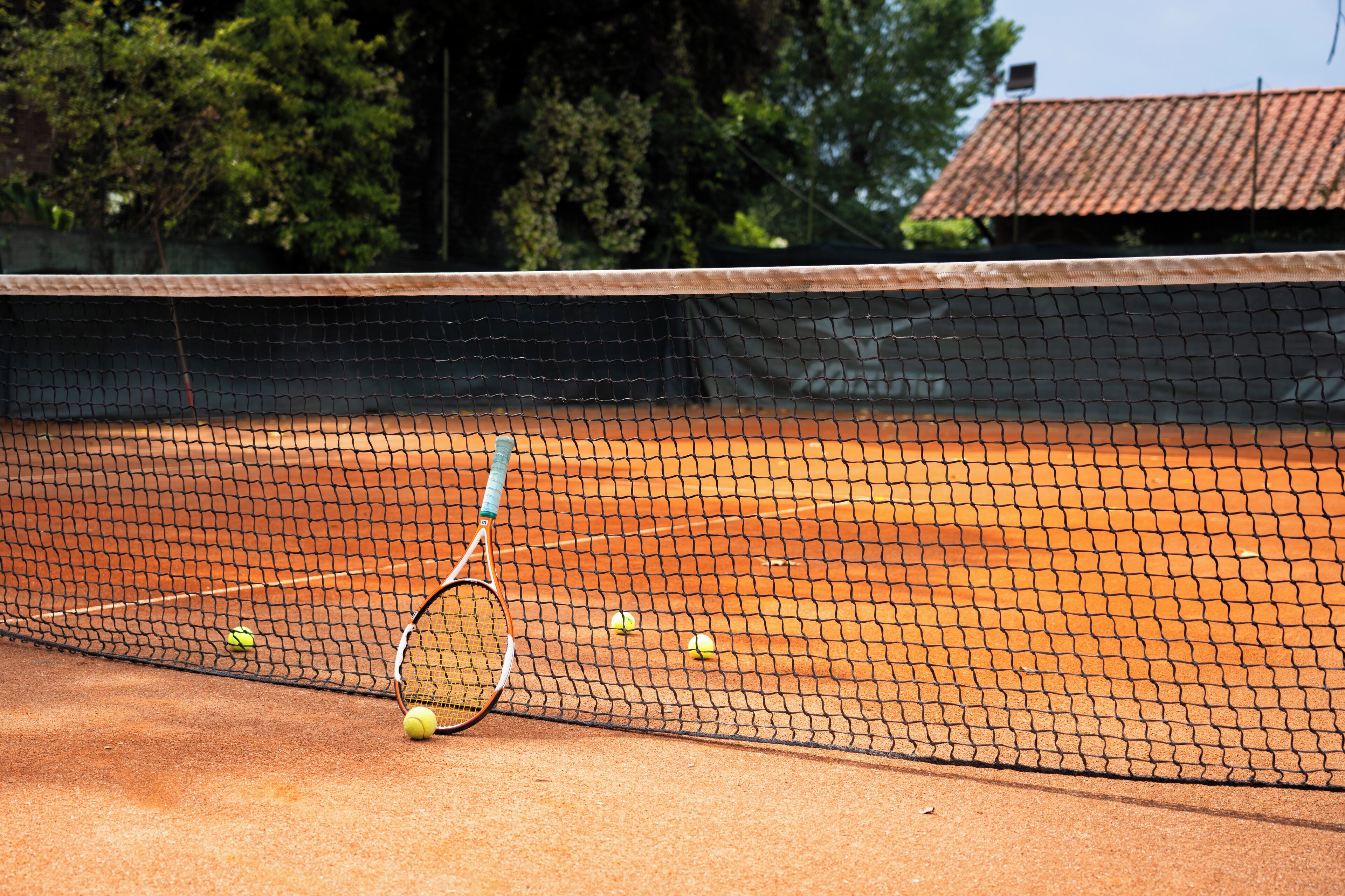 Un court de tennis avec un filet, des balles de tennis et une raquette.