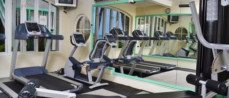 A gym with treadmills, weight machines, and a large mirror.