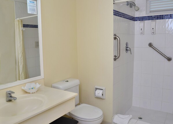 A bathroom with a toilet, sink, and shower. - Blue Orchids Beach Hotel (Worthing)