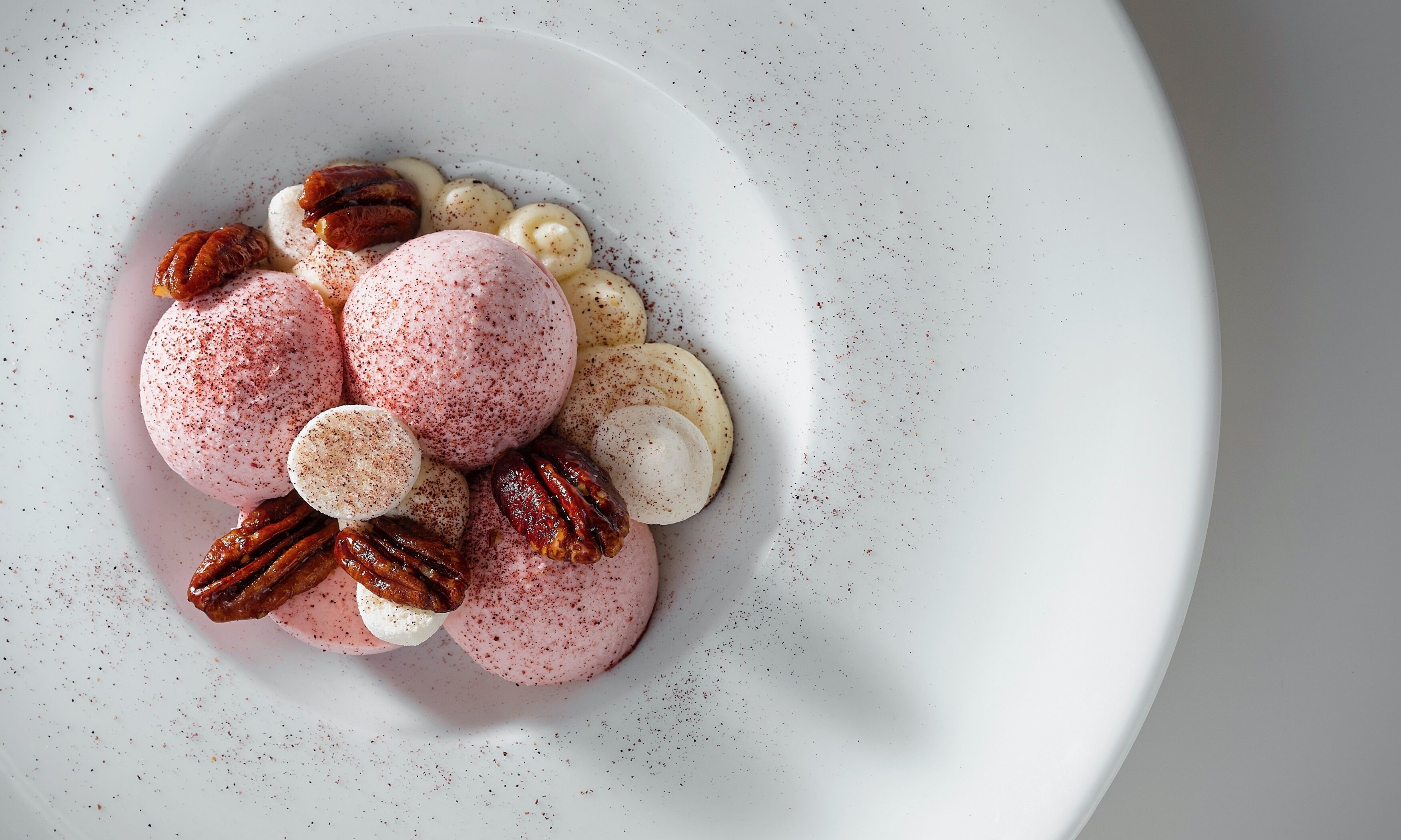 A dessert plate with macarons, pecans, and marshmallows.