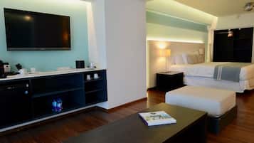 Camera d'albergo moderna con televisione a schermo piatto, divano, comodino e letto.