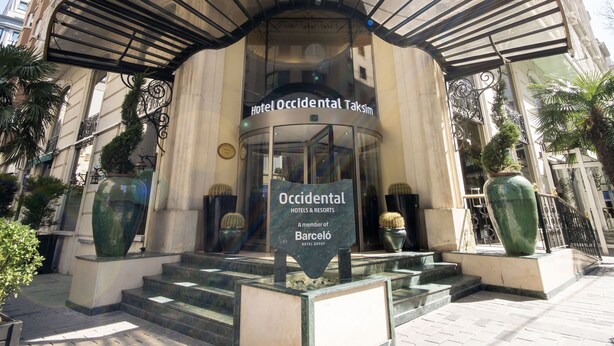 La entrada del Hotel Occidental Taksim, con fachada de vidrio, un dosel de entrada curvo y un cartel que indica que forma parte del Grupo Barceló.