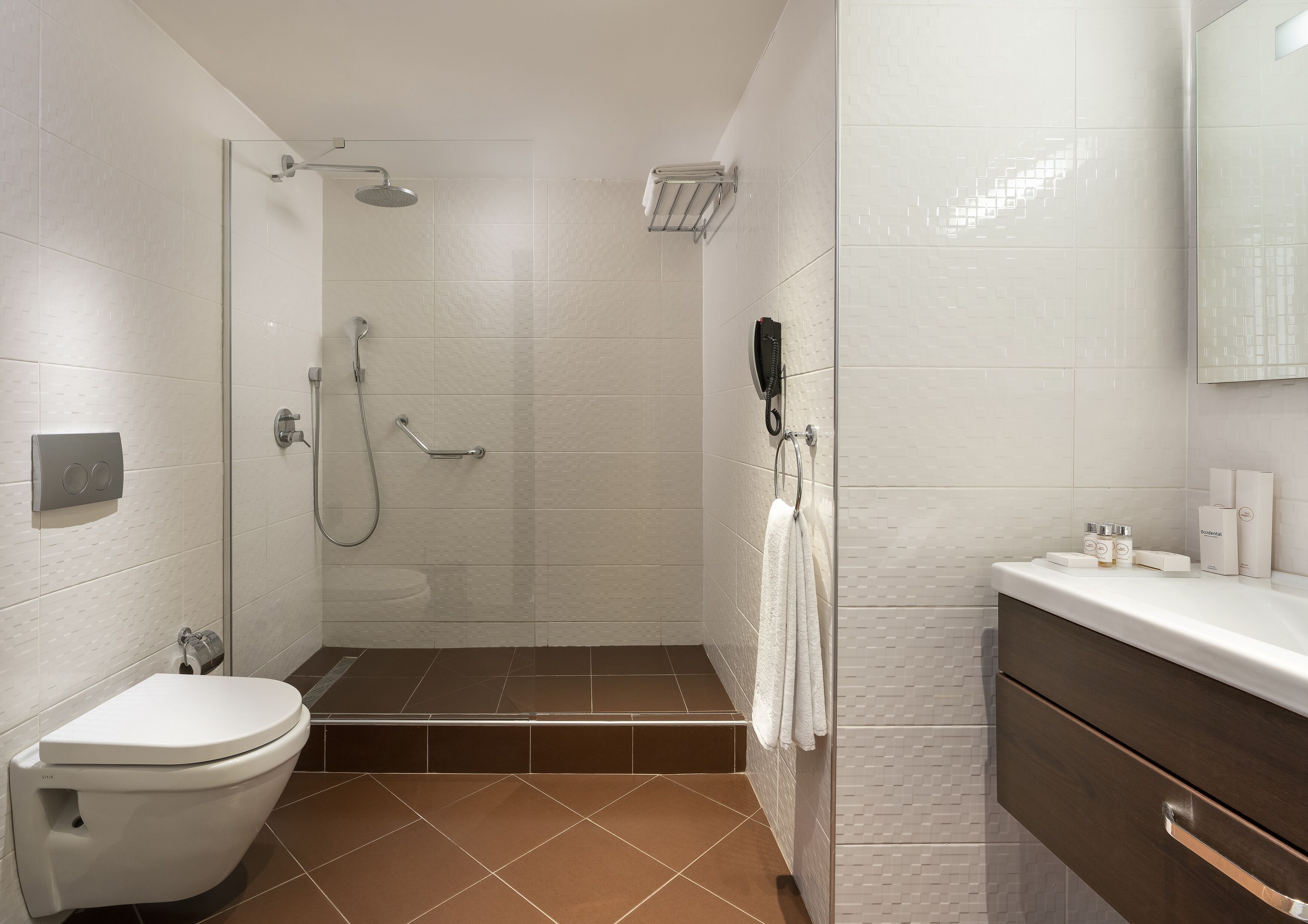 A modern bathroom with a toilet, shower, and vanity.