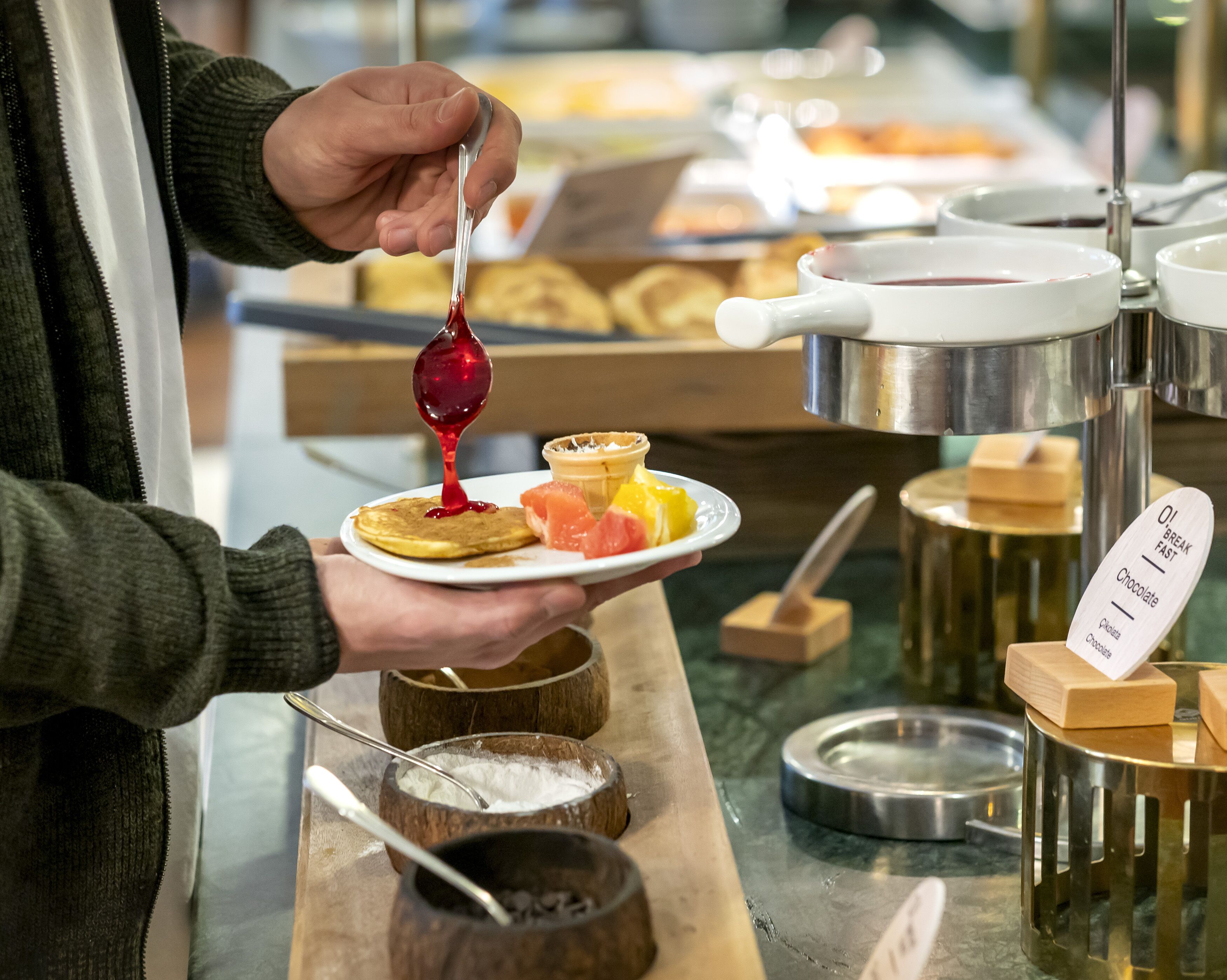 Eine Person gießt Sirup auf Pfannkuchen an einem Buffet.