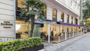 Hotel Occidental Taksim con una zona de estar al aire libre techada y un jardín bien cuidado.