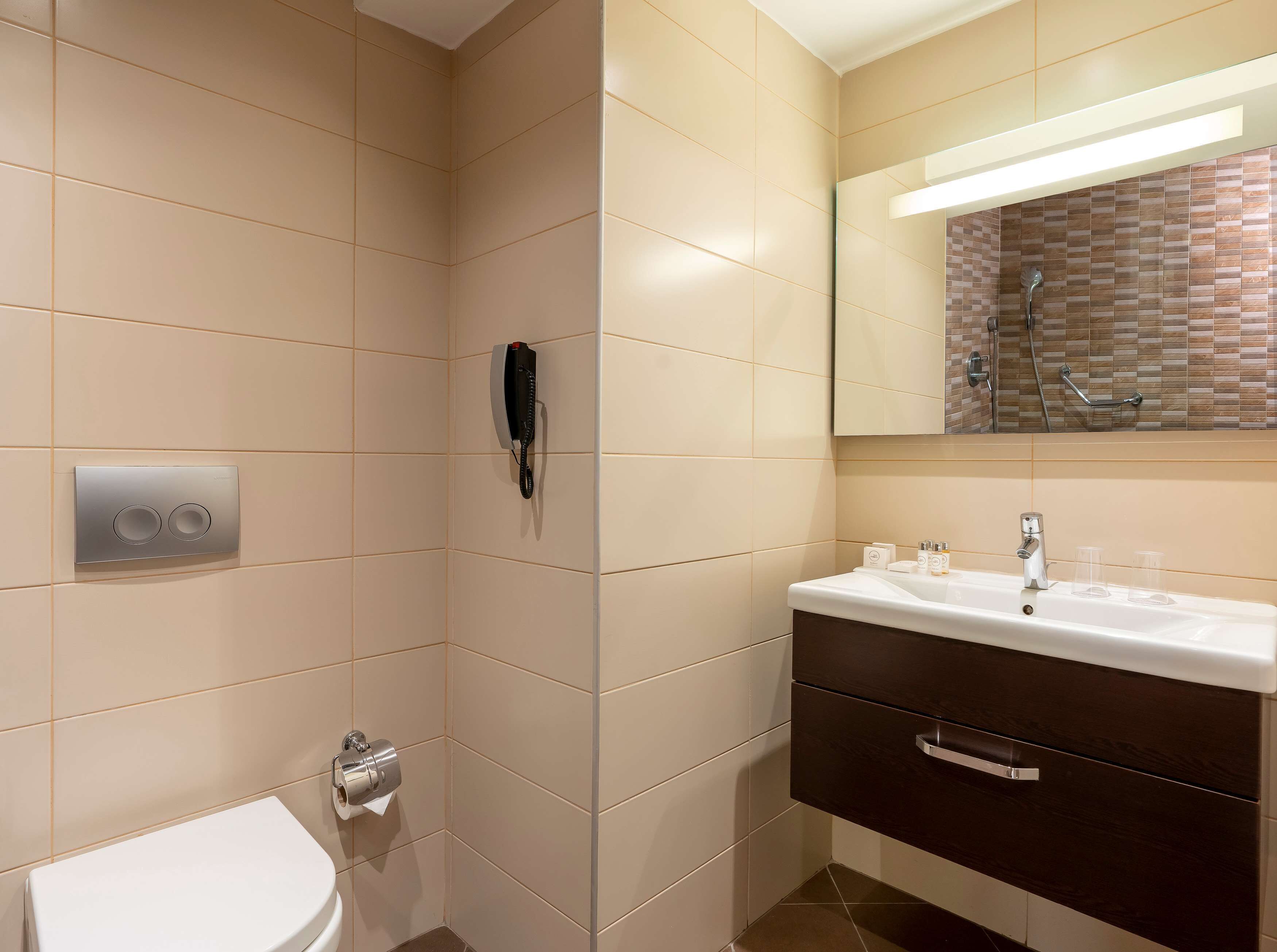 A modern bathroom with a toilet, a sink with a mirror, and a shower area.