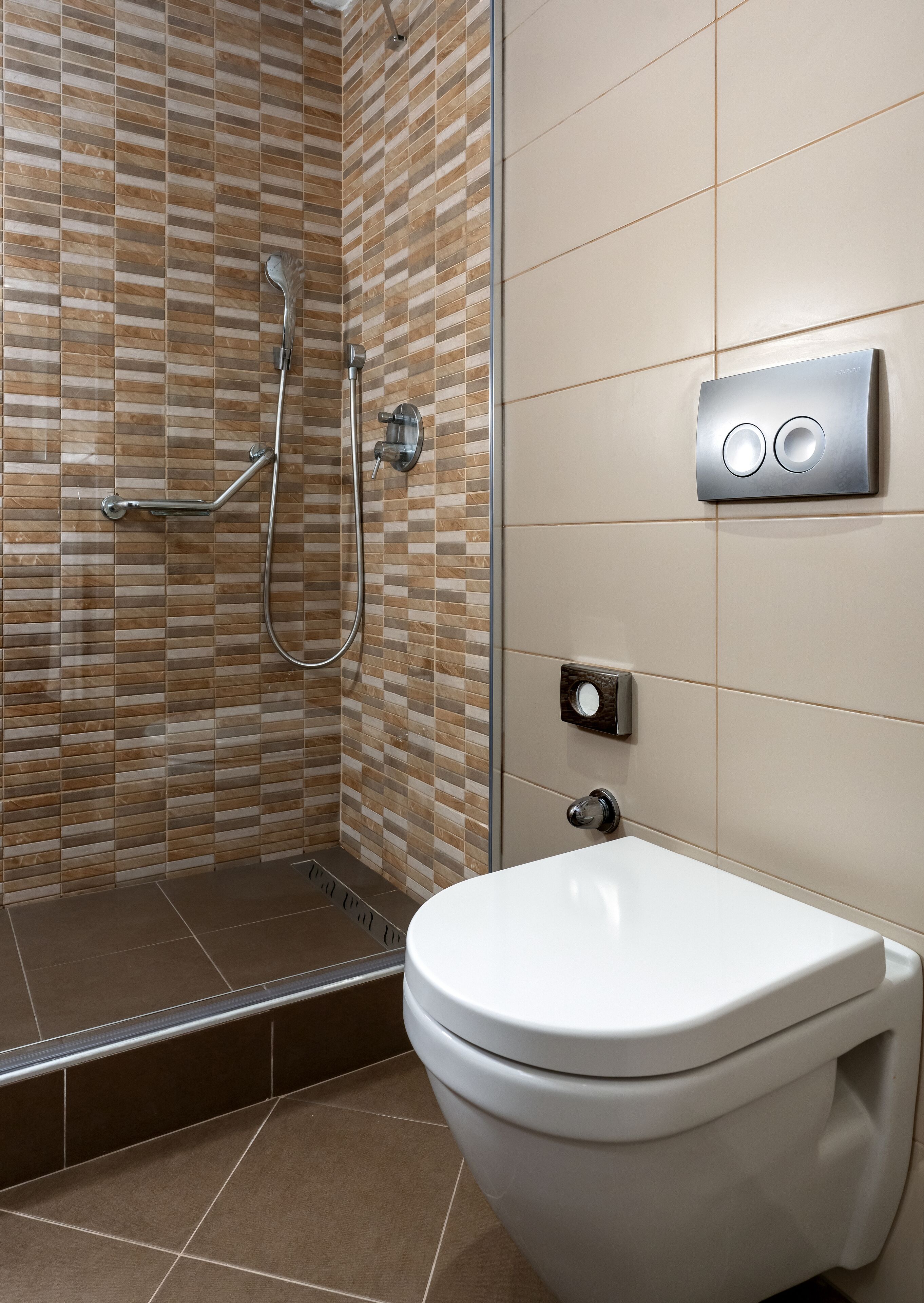 A bathroom with a shower, toilet, and a wall-mounted control panel.