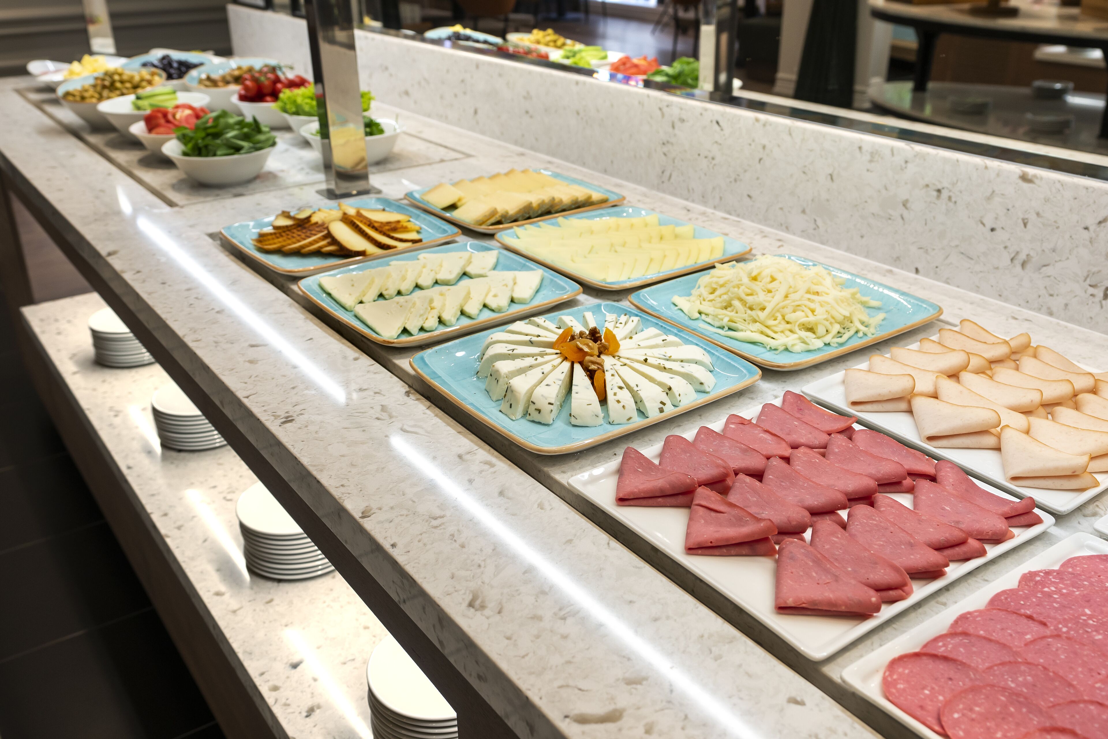 A buffet with various food items including cheese, meats, and salads.