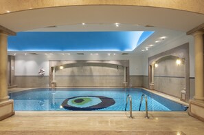 Swim beneath a clear blue ceiling in a pool with a unique circular mosaic design.