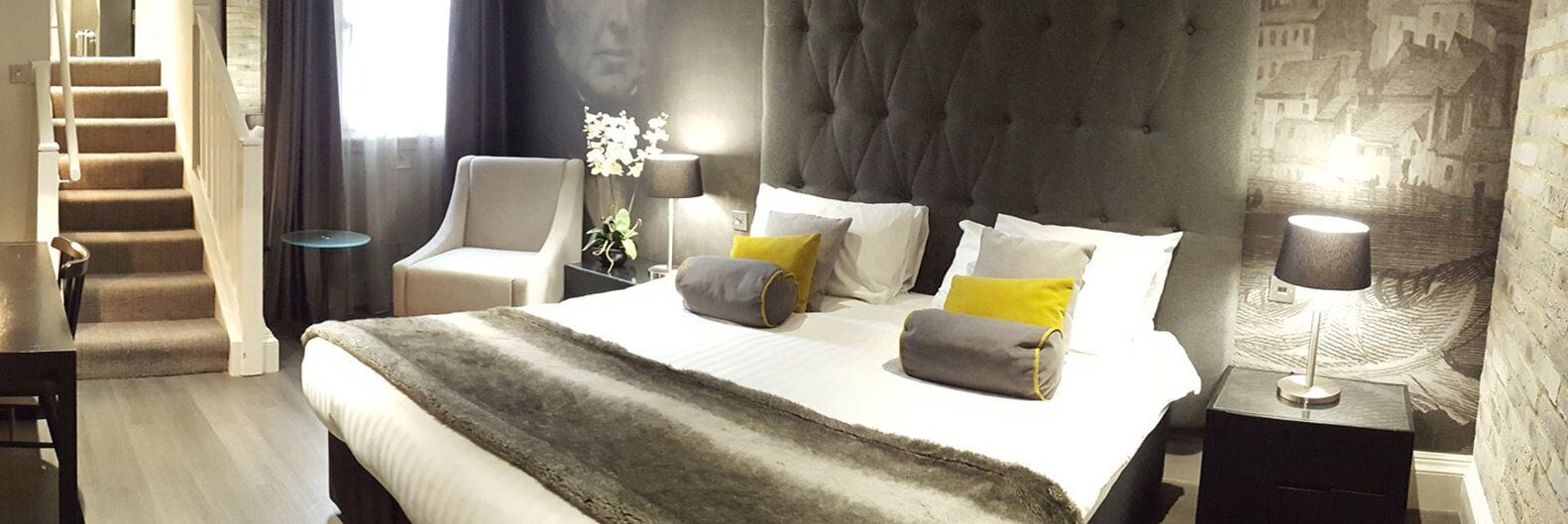 A hotel room with a large bed, a chair, a nightstand, and a lamp.