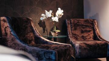 A room with two armchairs and a small table with a vase of white flowers.