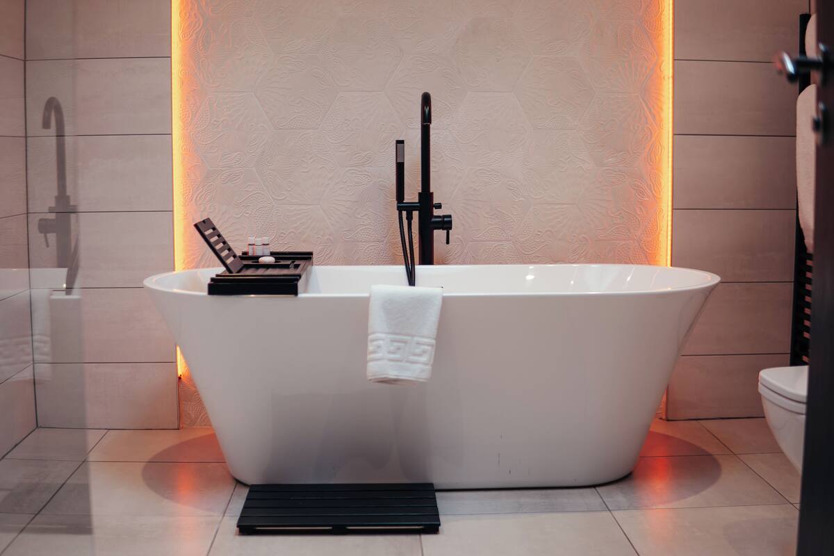 Ein modernes Badezimmer mit einer freistehenden Badewanne, einem Handtuch an der Seite und einer Duschbrause.