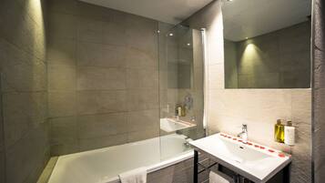 A modern bathroom with a glass shower enclosure, a bathtub, and a vanity with a mirror.