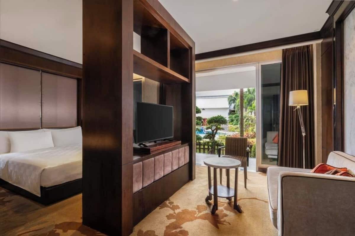 Une chambre d’hôtel avec un lit, une télévision, une petite table et un canapé.