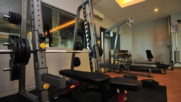 Un gimnasio con equipo de levantamiento de pesas, una banca y una cinta de correr.