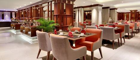 A modern restaurant with multiple dining tables and chairs, a central decorative wooden structure, and a well-lit interior.