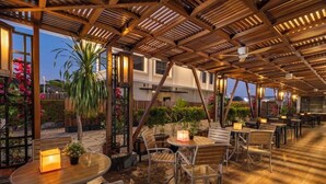 An outdoor patio area with wooden tables and chairs, surrounded by potted plants and flowers. - Swiss-Belhotel Borneo Banjarmasin (Banjarmasin)