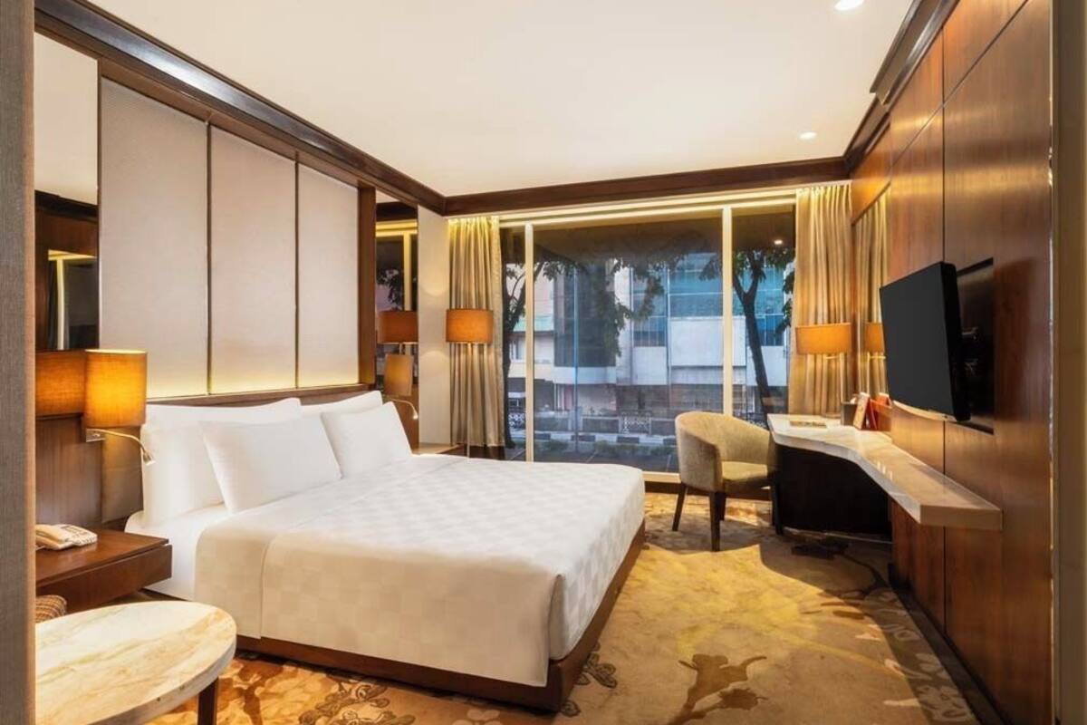 Une chambre d’hôtel avec un grand lit, un bureau, une télévision et une vue sur la ville.