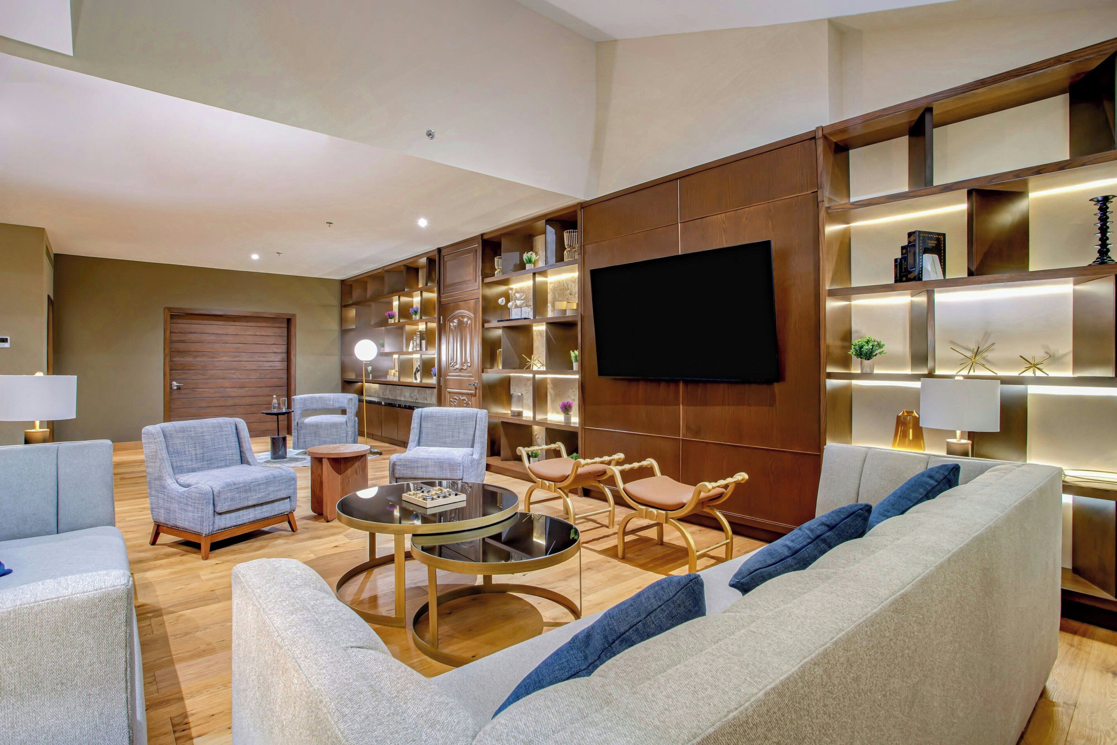 Una sala de estar moderna con sofá, sillones, una mesa de centro y un televisor montado en la pared.