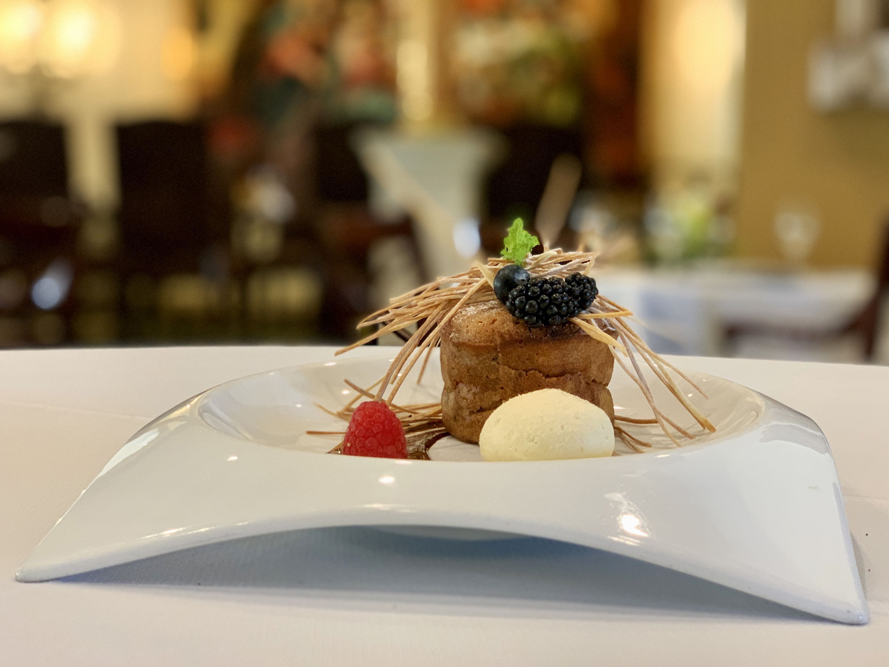 A dessert on a white plate with a clear glass dome.