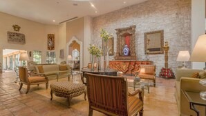A spacious lobby with a stone wall, classic furniture, and a central decorative area with a vase and mirror. - Casa Mayor Saltillo, Hotel Hacienda (Saltillo)
