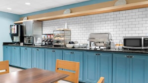 Cozinha moderna com armários azuis, estação de café e micro-ondas.