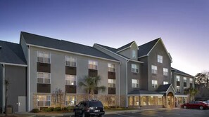 A multi-story hotel with a modern architectural design, featuring large windows and a parking lot in front.