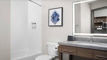 Un baño moderno con bañera, inodoro y tocador con un espejo grande.