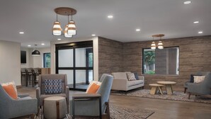 Una sala de estar moderna con un ventanal grande, un comedor y una cocina al fondo.