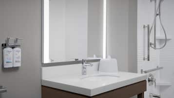 A modern bathroom with a white sink, a large mirror, and a shower area.