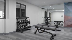 A modern gym with weight racks, benches, and exercise equipment.