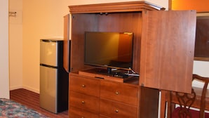 A compact room with a wooden cabinet containing a television and a refrigerator. - Travelers Inn (Dayton)