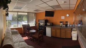 A room with a kitchenette, a dining area with a table and chairs, a bed, and a window with blinds. - Travelers Inn (Dayton)