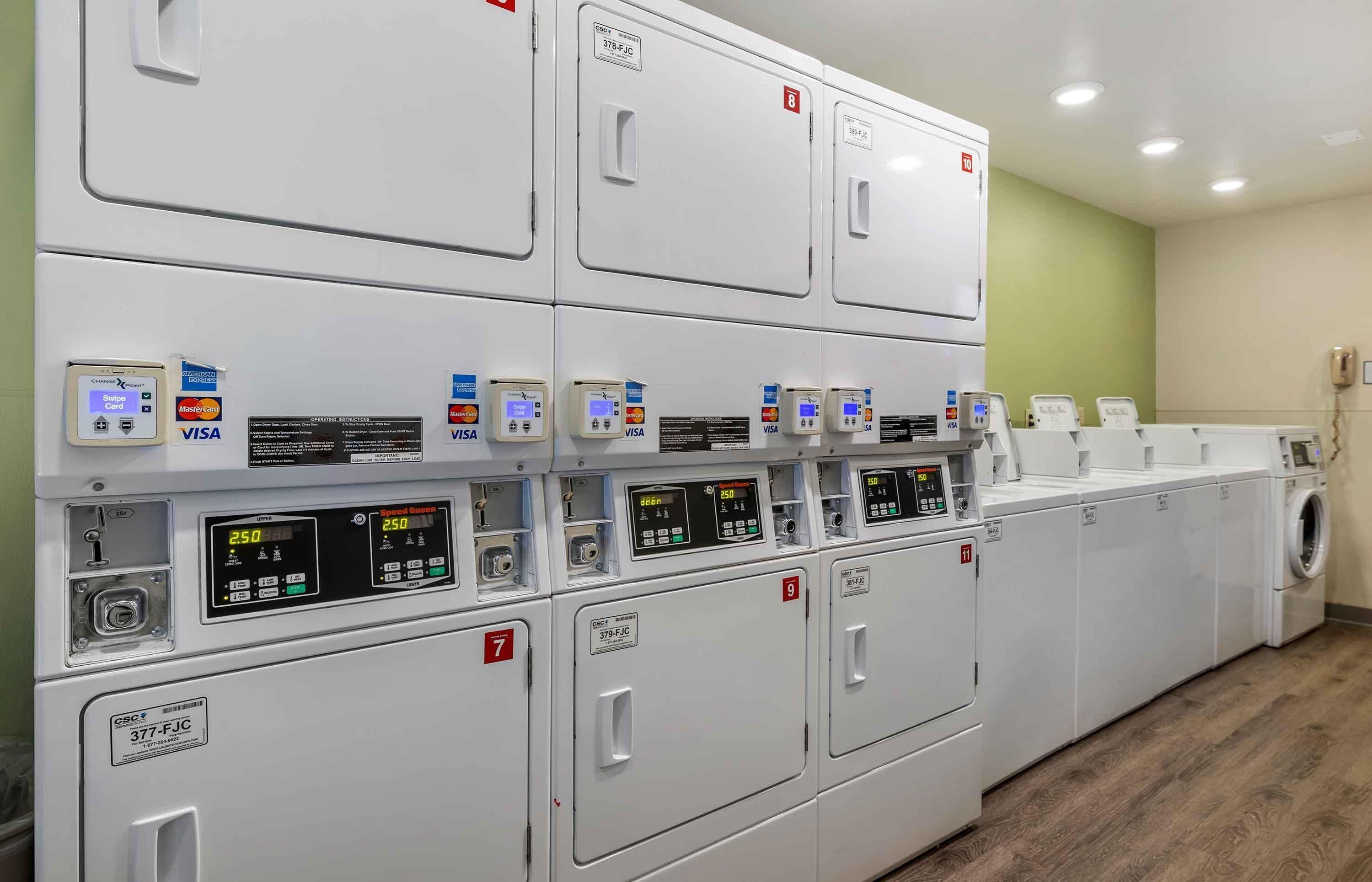 A laundry facility with multiple washing machines, card readers, and a control panel.
