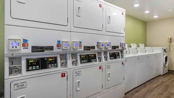 A laundry facility with multiple washing machines, card readers, and a control panel.